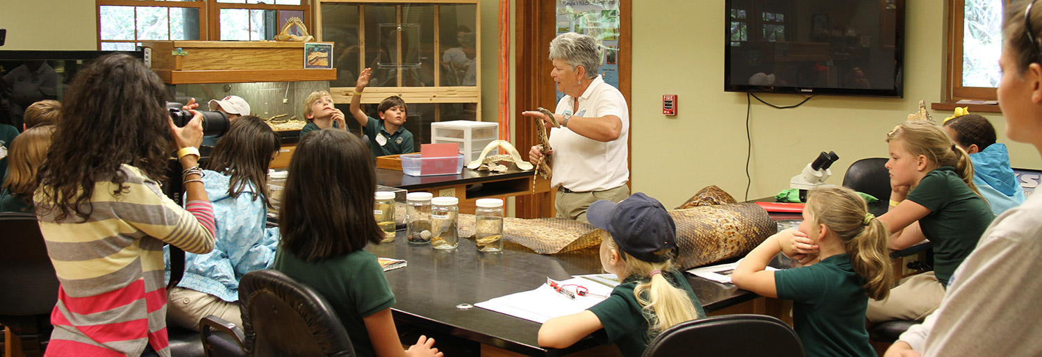 classroom of kids and instructor observing snakes