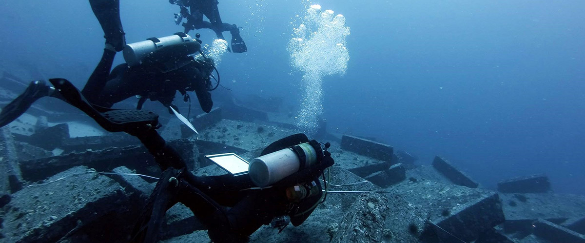scuba divers doing research at the bottom of the ocean